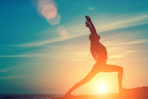 Silhouette of young woman doing exercises on the sea beach durin